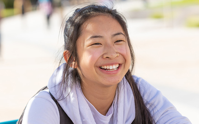 female student smiling outside wearing a purple sweatshirt 